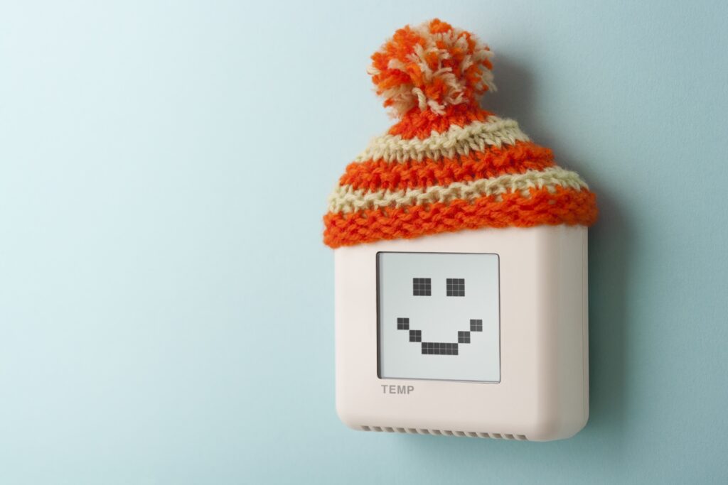 thermostat on wall with hat and smiley face
